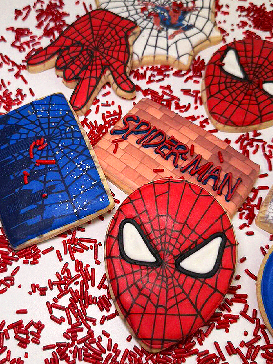 Assorted Spiderman cookies with red and blue icing on sprinkles.