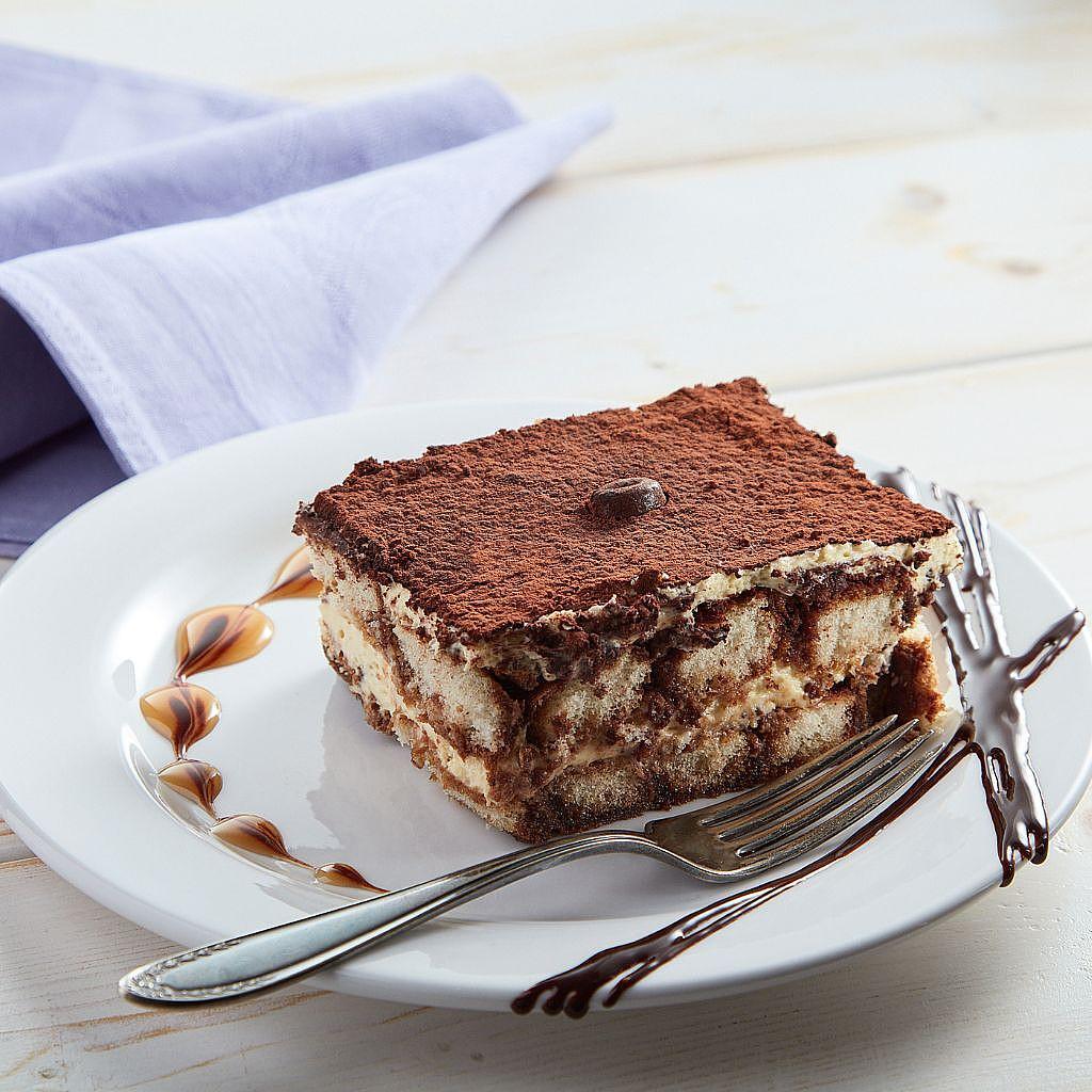 Square slice of tiramisu on a white plate with a fork