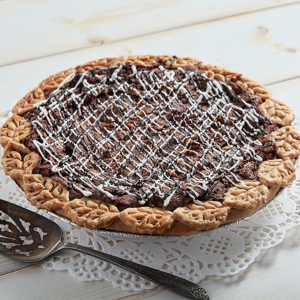 Fudge pecan pie with decorative leaf crust and icing drizzle.