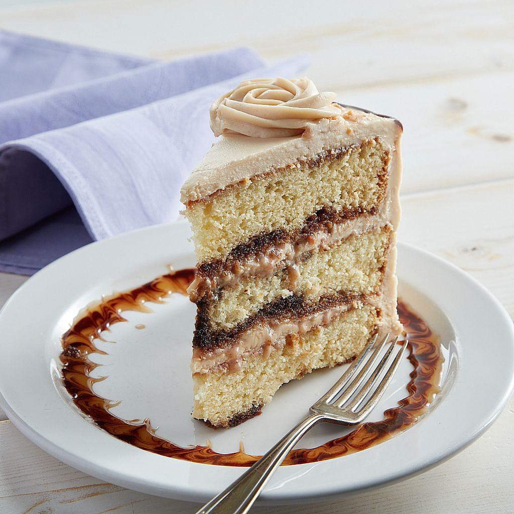 Slice of layered cake with frosting on a white plate