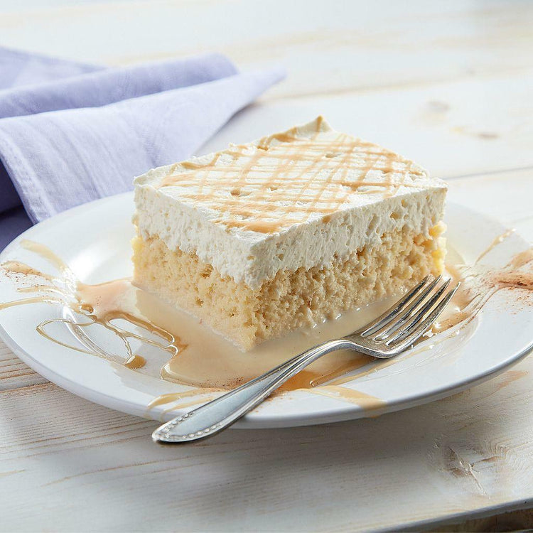 Tres Leches slice with whipped topping on a white plate