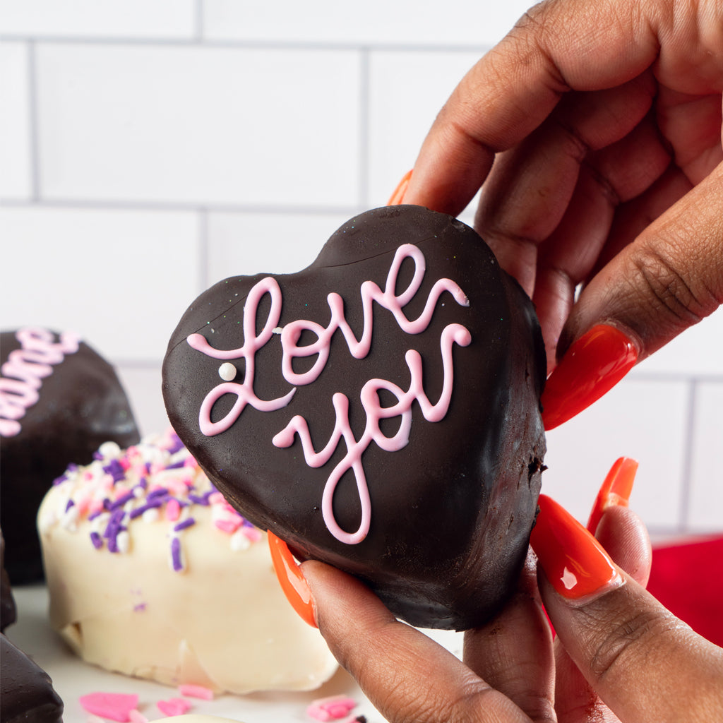 Petit Four Hearts with pink icing held in hand