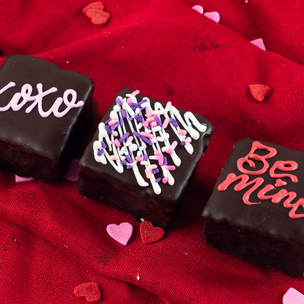 Valentine Petit Fours decorated with icing on red fabric.