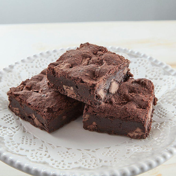 Three vegan brownies on a white lace doily.