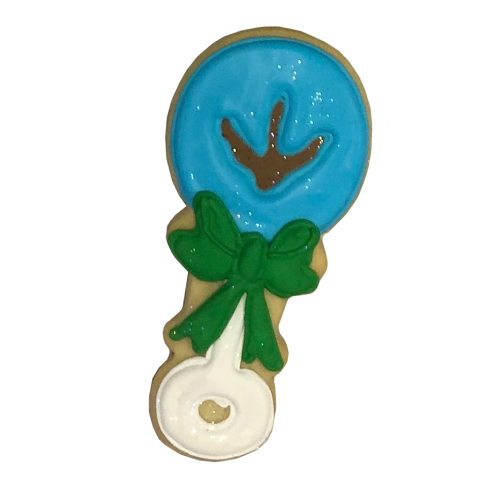 Dino rattle cookie with blue icing and a green bow.