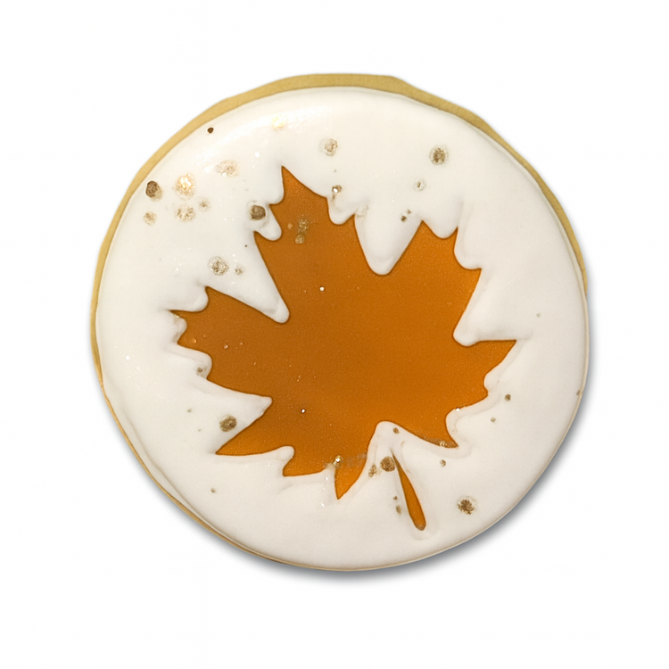 Fall cookie with white icing and an orange maple leaf design.