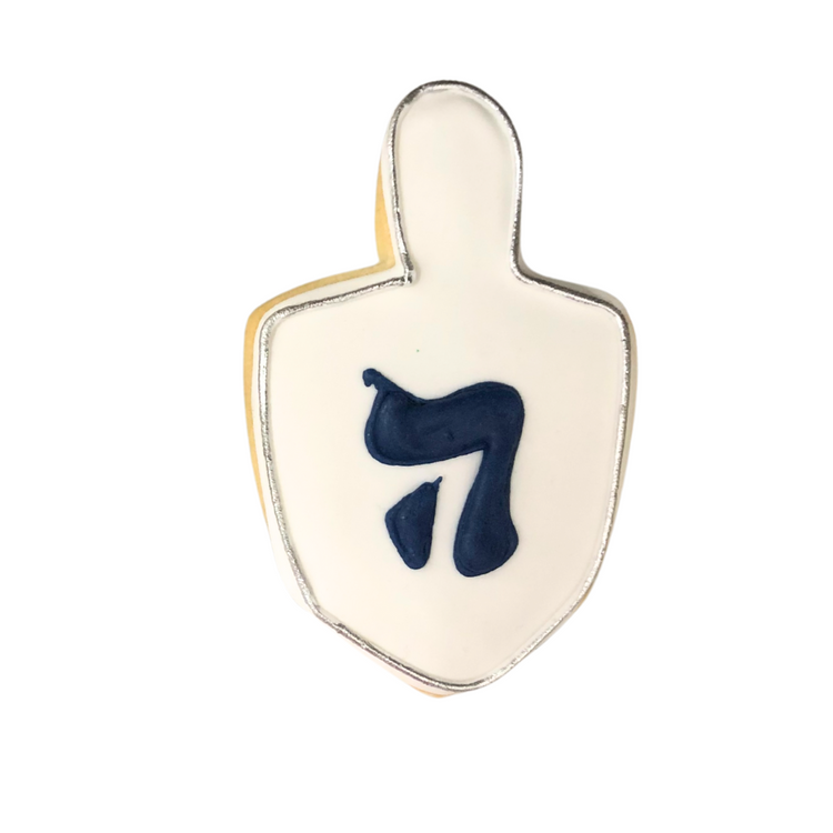 Hanukkah cookie shaped like a dreidel with blue Hebrew letter.