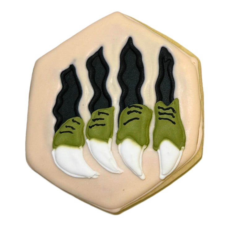 Hexagonal Jurassic cookie with green and white dinosaur claws.