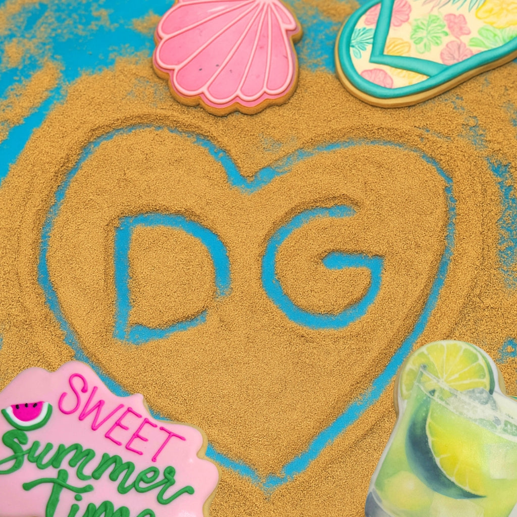 Assorted summer cookies on blue sand with a heart design.