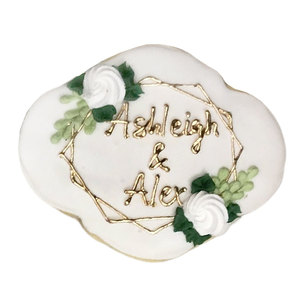 Wedding plaque cookie with gold names and floral accents.