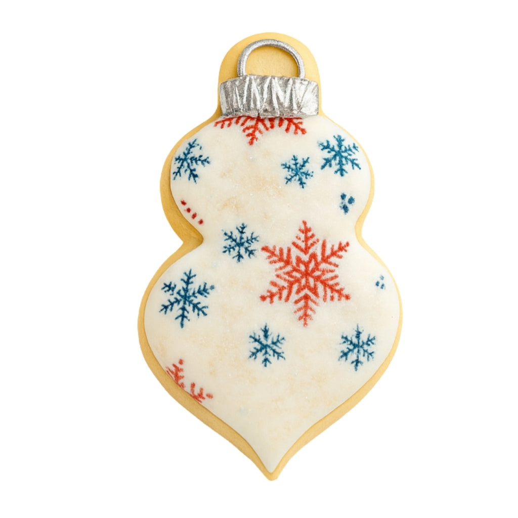 Ornament cookie with red and blue snowflake icing patterns.