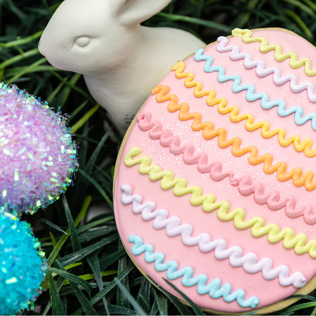 Easter butter cookie with pink icing and colorful zigzags.