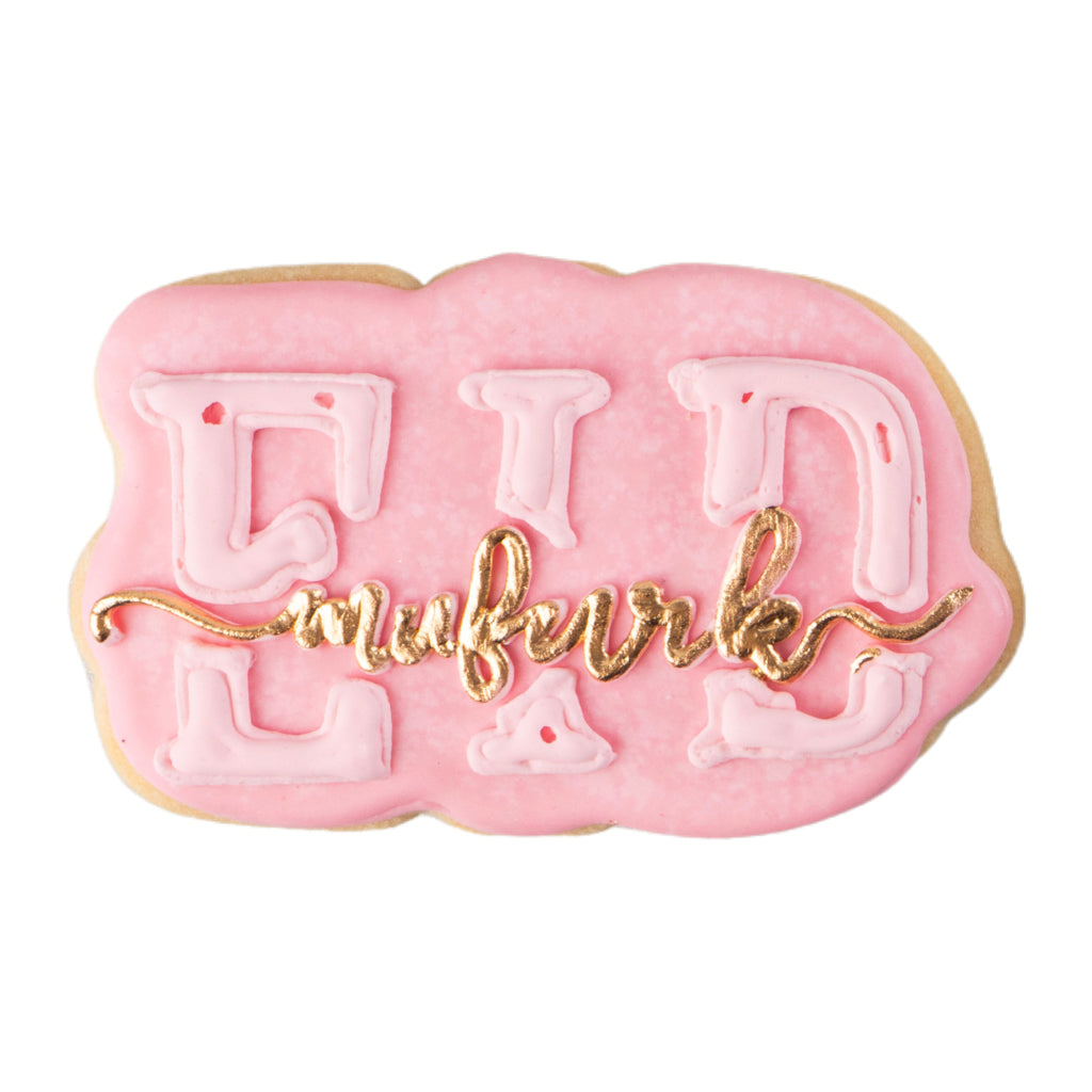 Eid Mubarak butter cookie with pink icing and gold lettering.