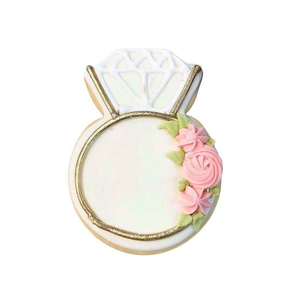 Diamond ring-shaped cookie decorated with pink icing flowers.