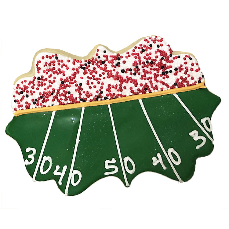 Football stadium cookie with green field and red sprinkles.