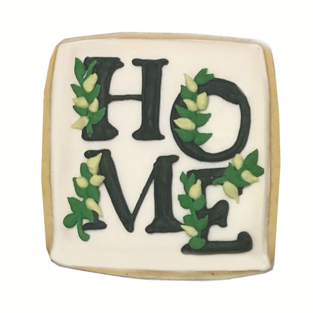 Square Home plaque cookie with black lettering and green leaves.
