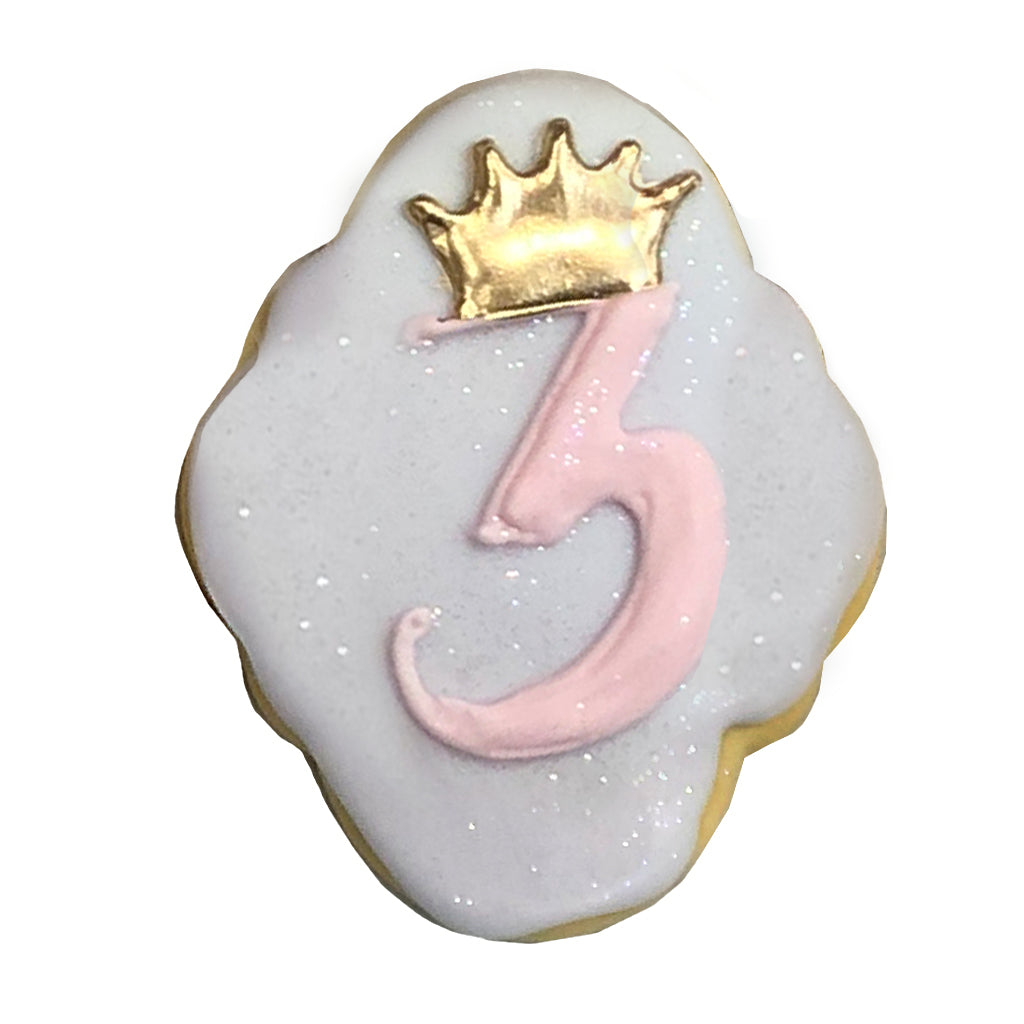 Princess 3 cookie with pink icing and a gold crown topper.