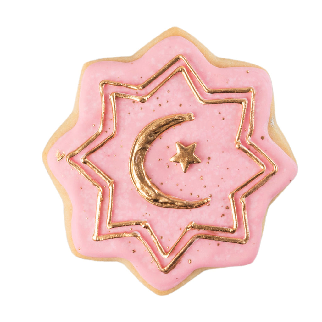 Star-shaped Ramadan butter cookie with pink icing and gold trim.