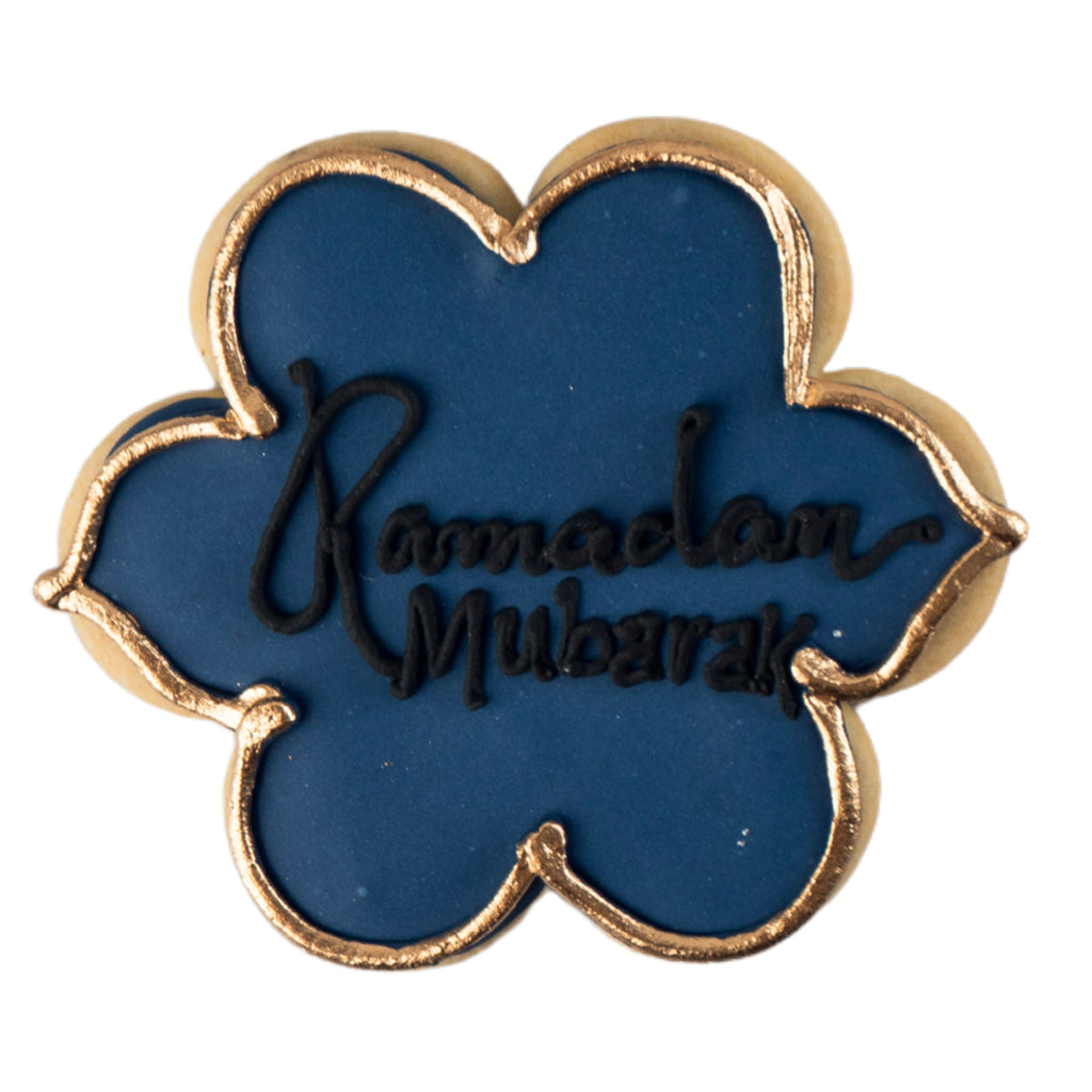 Flower-shaped Ramadan butter cookie with blue icing and gold trim.