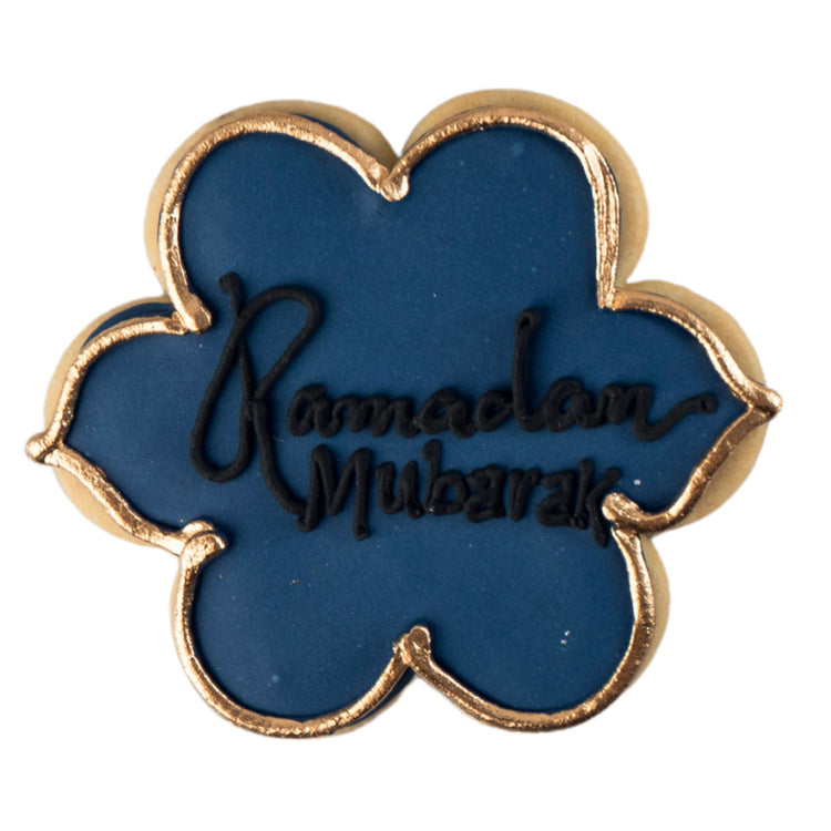 Flower-shaped Ramadan butter cookie with blue icing and gold trim.