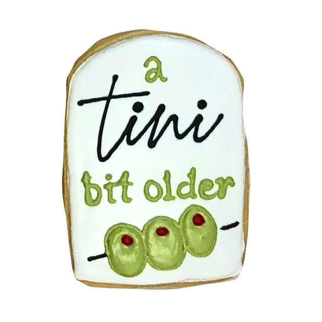 A Tini Bit Older cookie decorated with three green olives.
