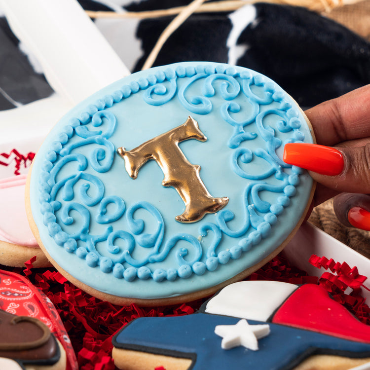 Cowboy Couture cookie with blue icing and gold letter T