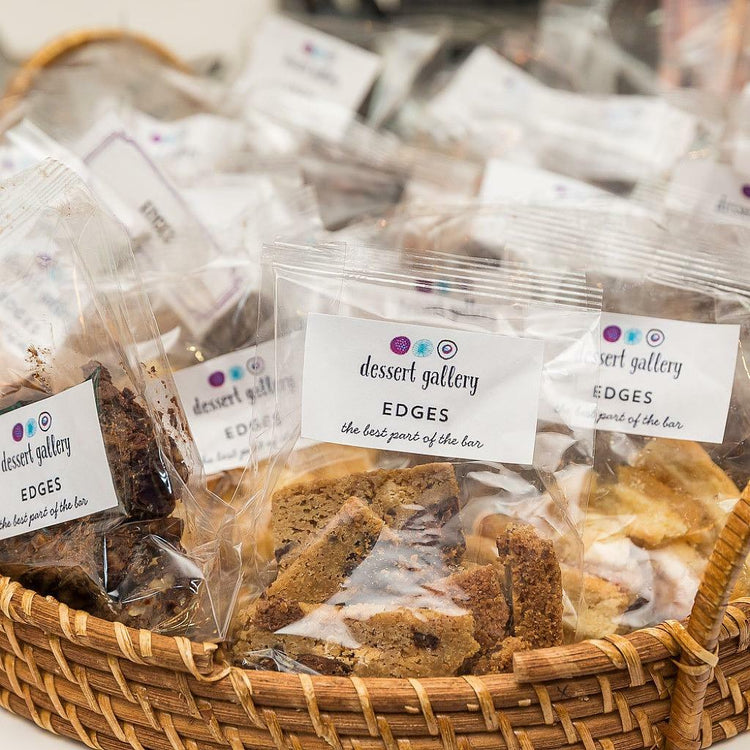 Edges dessert bars in clear plastic bags inside a wicker basket.